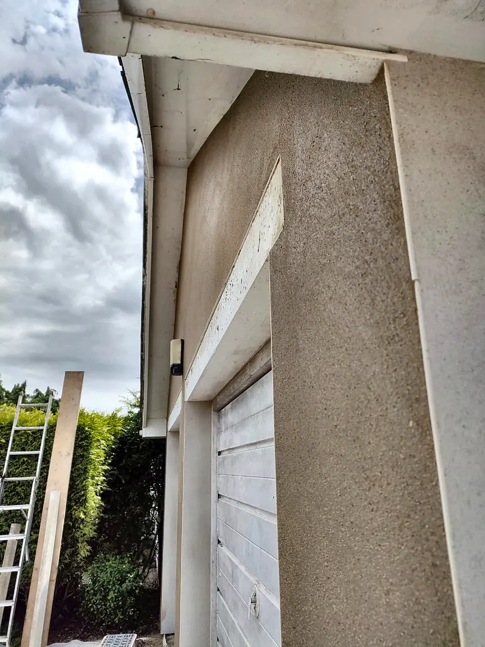 Close-up of textured render finish beside a white garage door