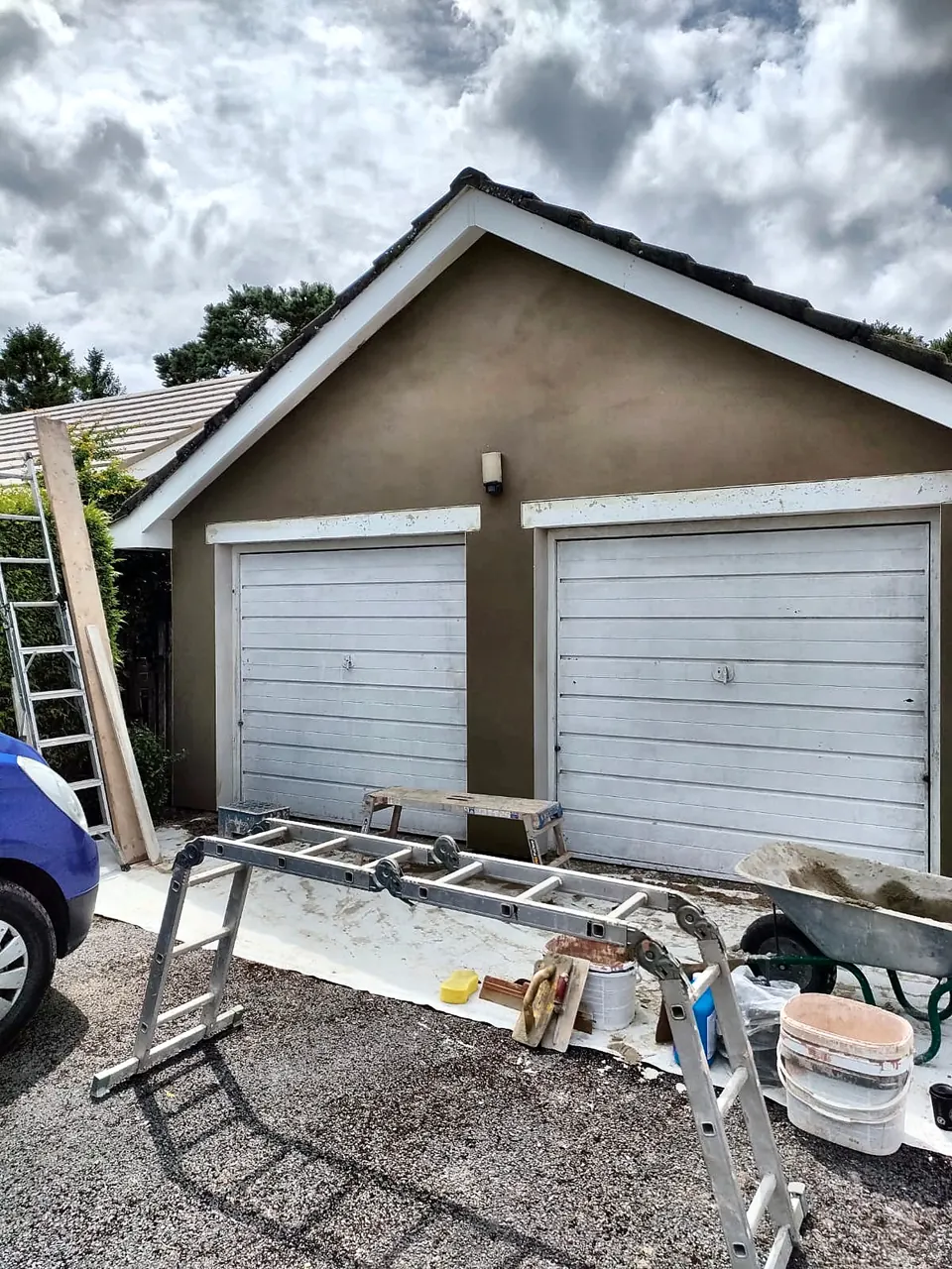 Double garage with a freshly rendered front and two white up-and-over doors