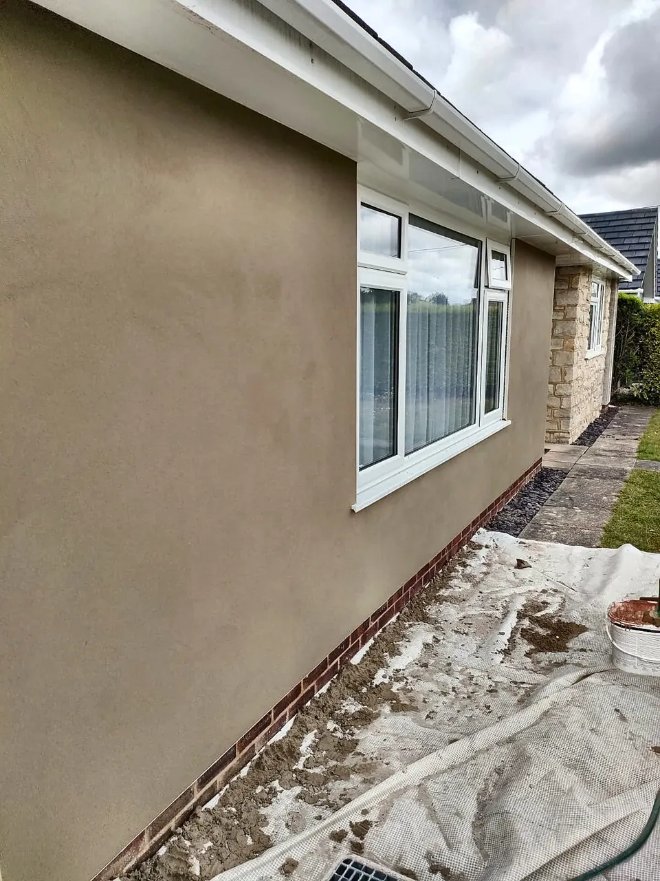 Finished smooth render on the side of a bungalow with a white window