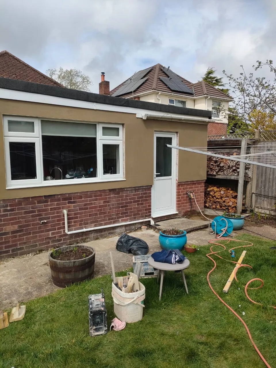 Finished smooth render on the rear of a bungalow with a large window and white door