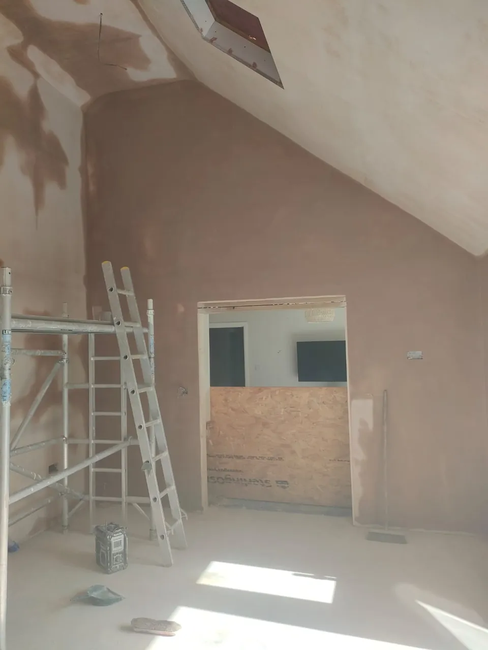 Skimmed vaulted ceiling and walls with a roof window opening, drying in patches