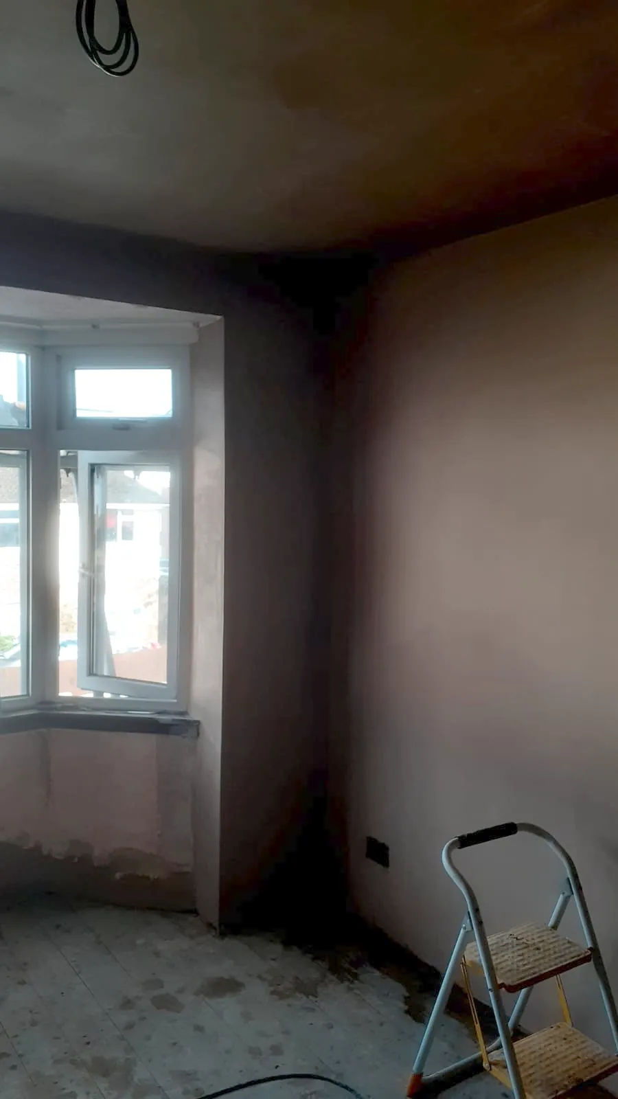 Newly plastered bay window room with a step ladder, the walls and ceiling skimmed