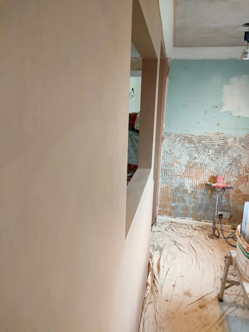 Smooth new plaster beside an old stripped wall waiting to be plastered