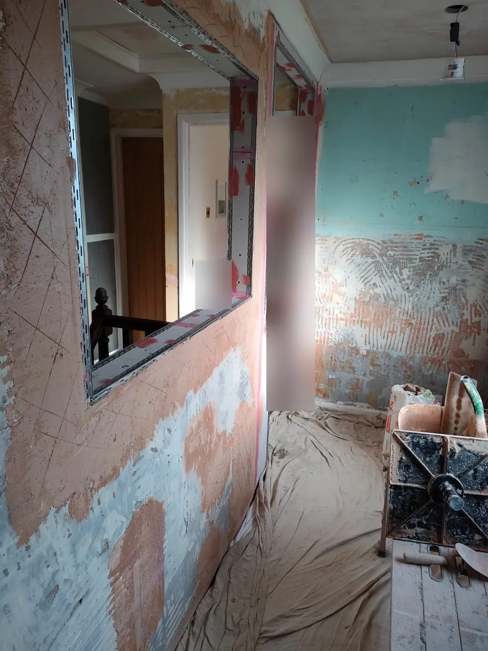 Landing wall with the scratched undercoat applied and beads fitted around an opening to the stairs